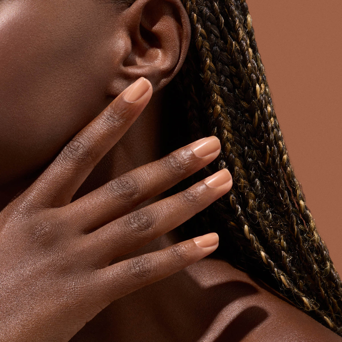 Main aux ongles nude chaud près de l’oreille