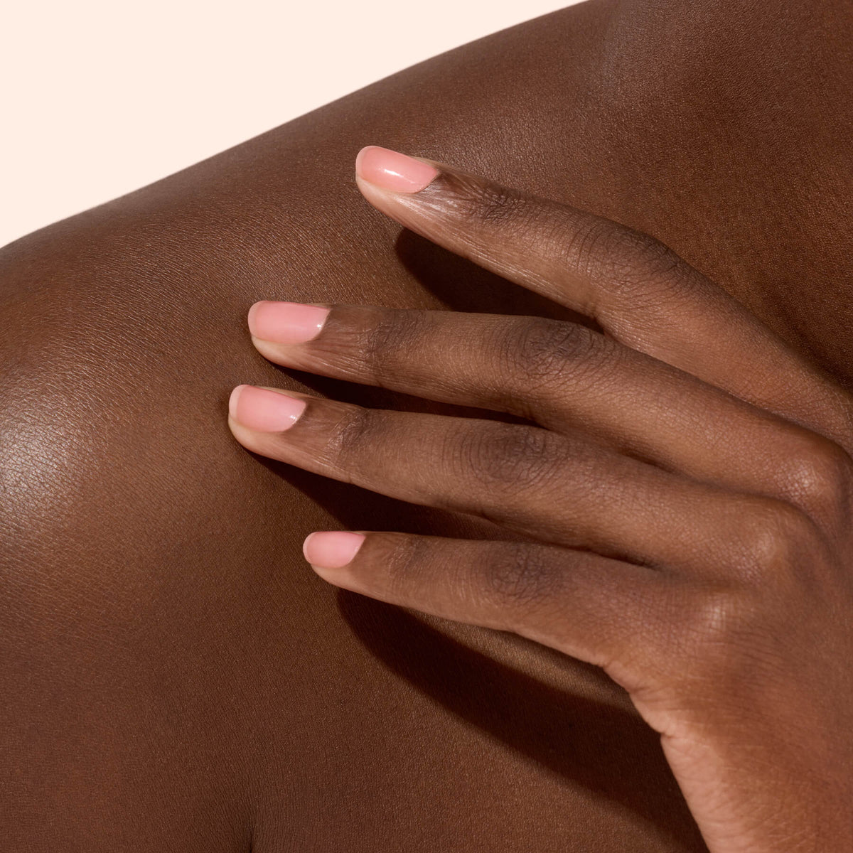 Main aux ongles rose doux sur épaule